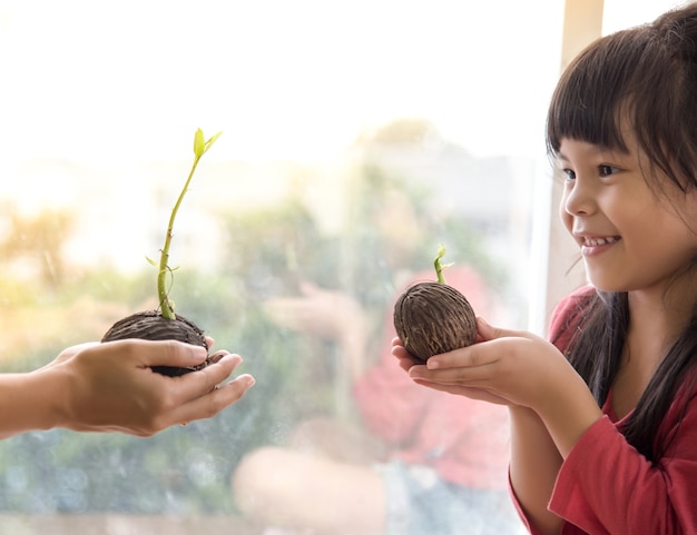 大人の手から小さな植物を保持している少女の子供の手