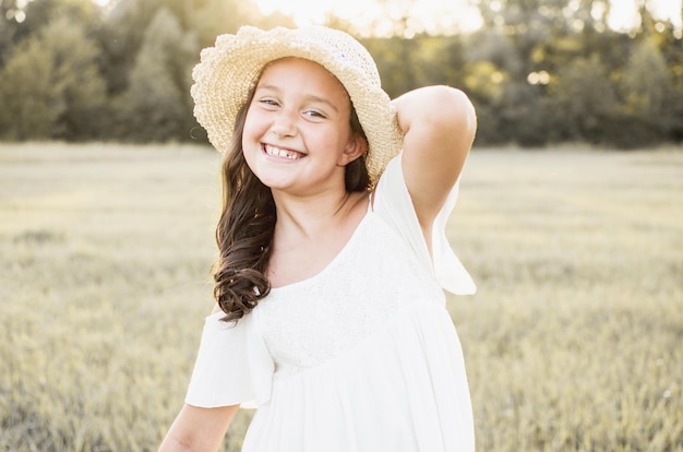 写真 日光の下でのんきな笑顔と笑い自然を楽しんでいる夏の小さな女児