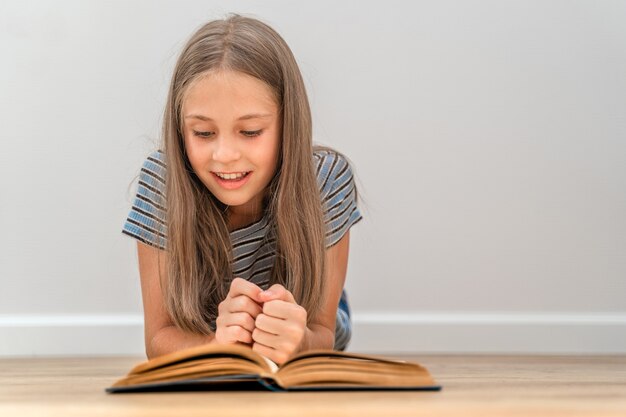 小さな女児が部屋の床に横になって本を読んでいます