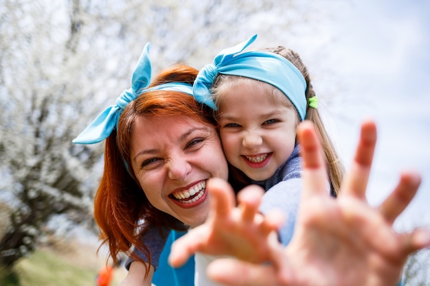 Little girl child and mother woman walks through the spring forest with flowering trees, laugh and play, the beginning of spring, family vacation, love of parents