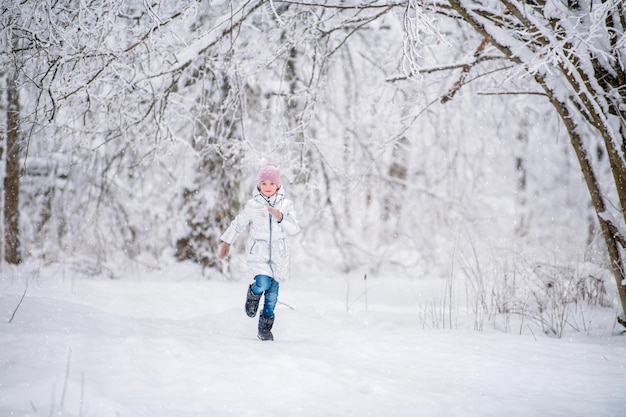 Маленькая девочка, бегущая зимой в снежном парке