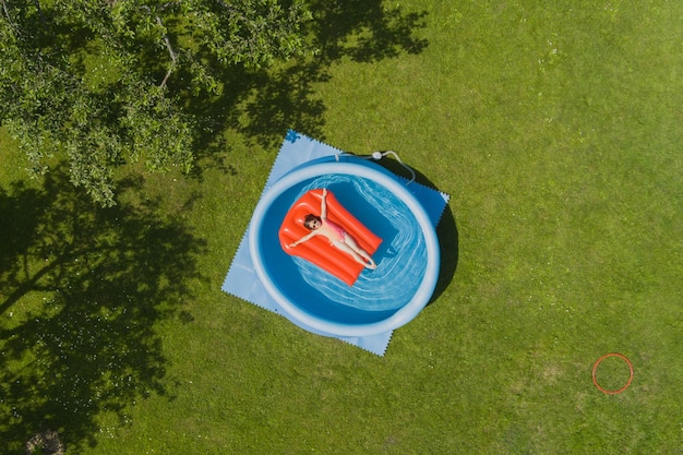 little girl child sunbathes on an air mattress in a swimming pool outdoors on a summer day