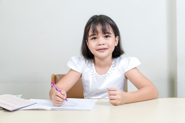 家で宿題や自習をしているノートに書いている小さな女の子の子供たちの学生