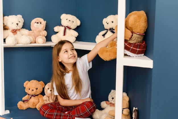 Una bambina sceglie gli orsacchiotti in una cartolina di natale del negozio di natale