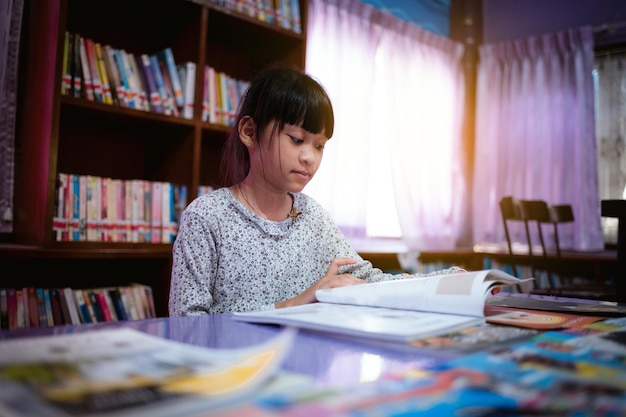 Little girl choosing book in public library room selecting literature for reading girl chooses book