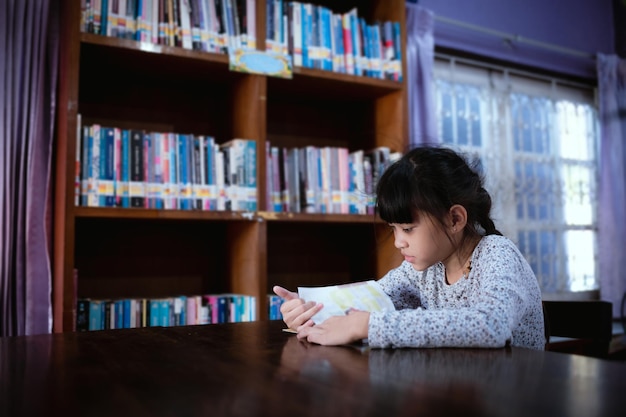 Little girl choosing book in public library room selecting literature for reading girl chooses book