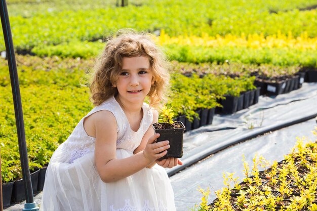 Little girl choosing plant in pot for her mother