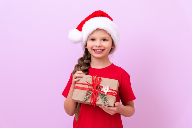 A little girl in a Christmas hat is very happy with her gift. The child is happy about the new year.