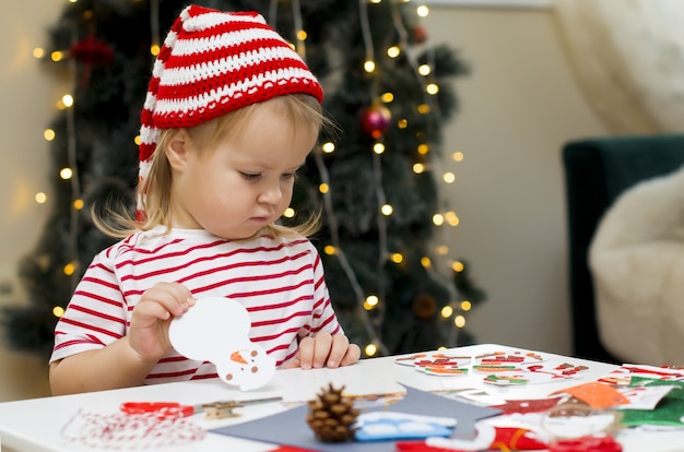 クリスマスの子供たちの創造性とクリスマスの工芸品の装飾を作るクリスマス帽子の少女