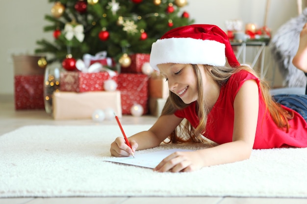 Photo little girl in christmas interior writes a letter to santa claus