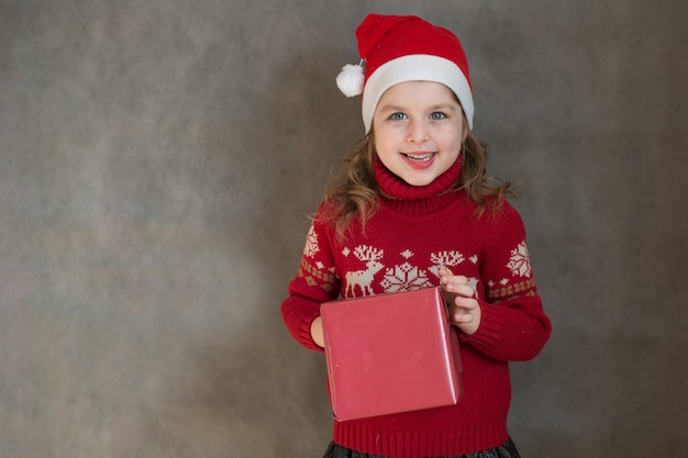 Little girl in Christmas sweater holding a present