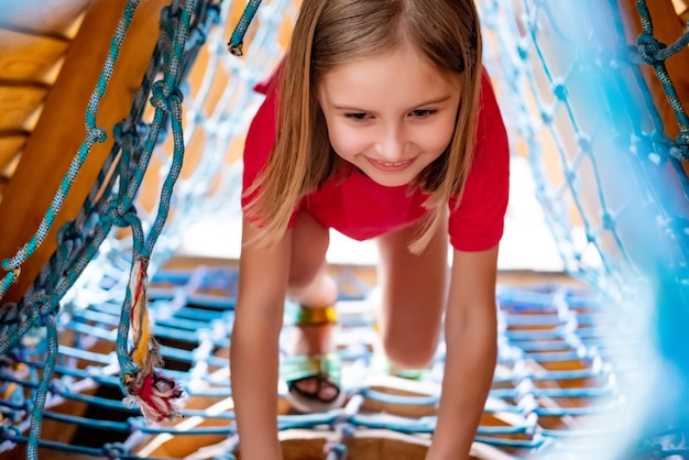 Little girl climbing throught net on playground in park