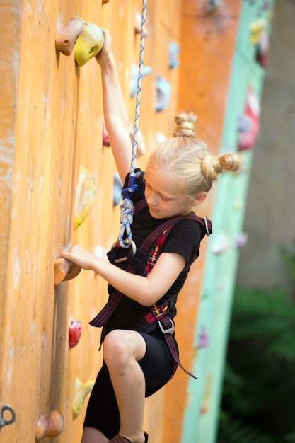 Little girl climbing up the bouldering wall