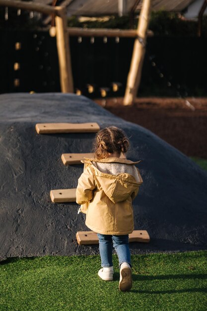 La bambina si arrampica su per la collina nel parco giochi con molta energia