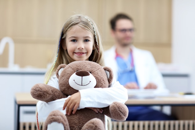 little girl in clinic with pediatrician in the background