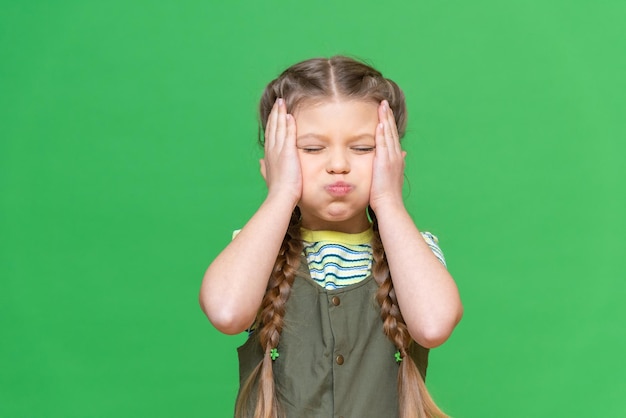 The little girl clutched her head with her hands and puffed out her cheeks. Isolated background.