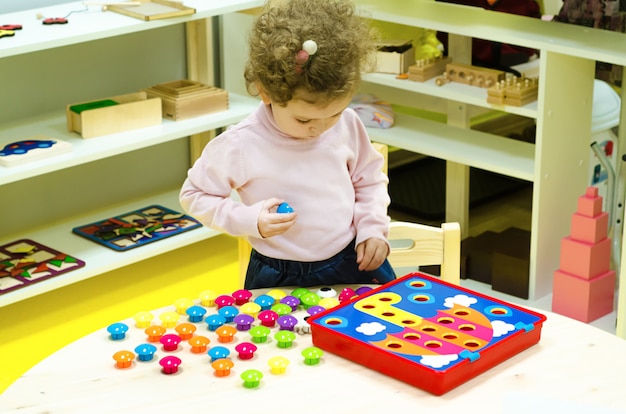 Little girl collects a puzzle.