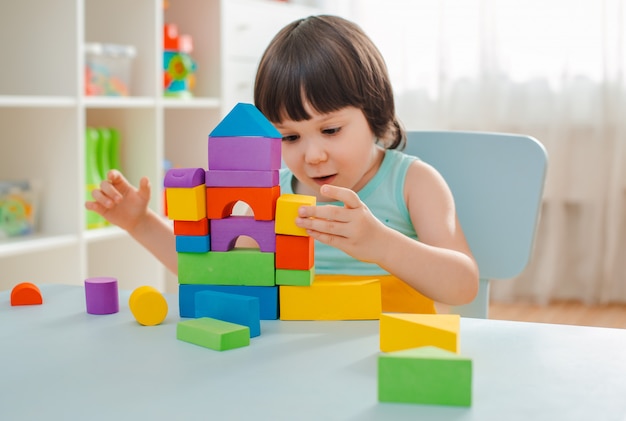 Little girl collects a wooden unpainted pyramid. Safe natural wooden children's toys.