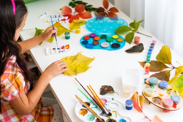 写真 小さな女の子は家で紅葉を着色します