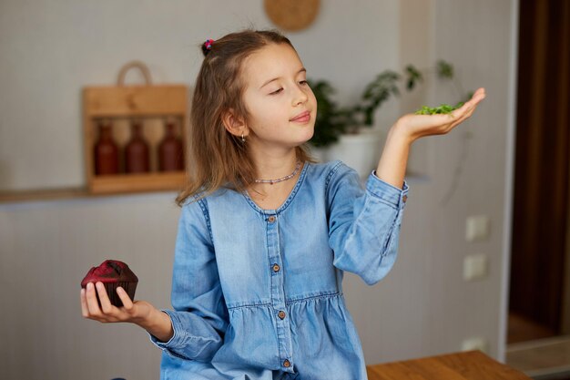 Little girl comparing food choosing microgreen against sweet cake Healthy dieting habit