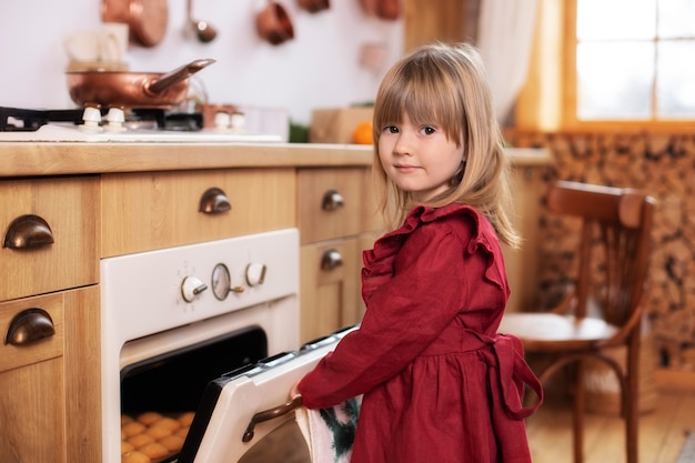 Little girl cooking christmas cookie in oven in kitchen