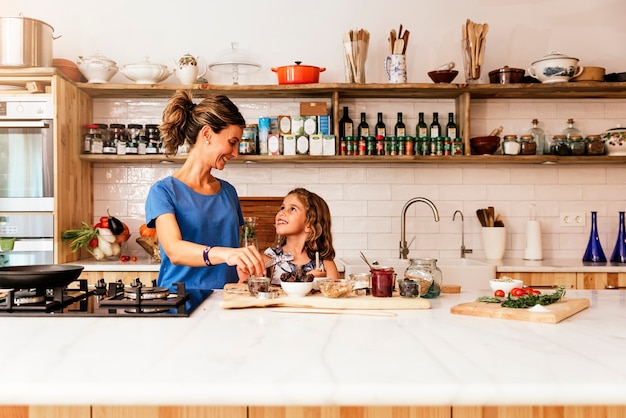 Bambina che cucina con sua madre in cucina. concetto di chef infantile.