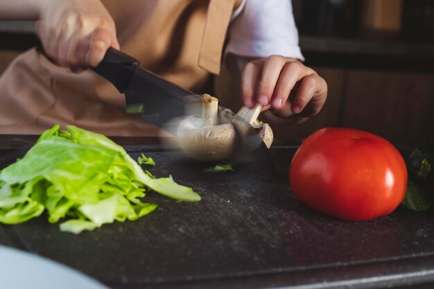 Little girl cooks on the kitchen preparing ingredients cutting vegetables in motion shot