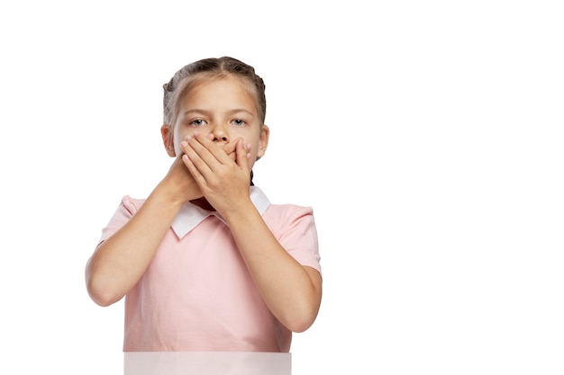 The little girl covered her mouth with her hands. Isolated over white background.