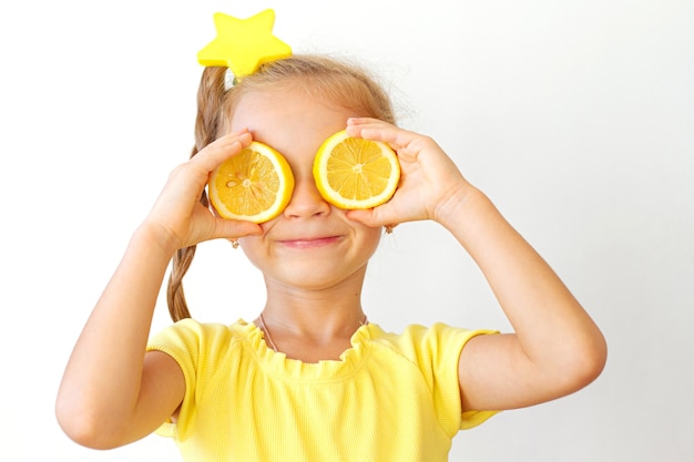 Photo little girl covering her eyes with lemon slices