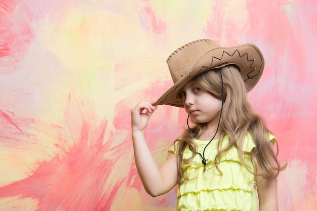 Little girl in cowboy hat on colorful background, copy space