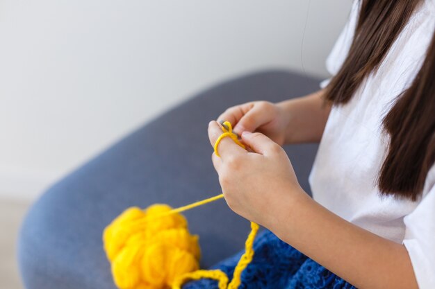 little girl crochets with yellow threads. Top view. Making decoration.