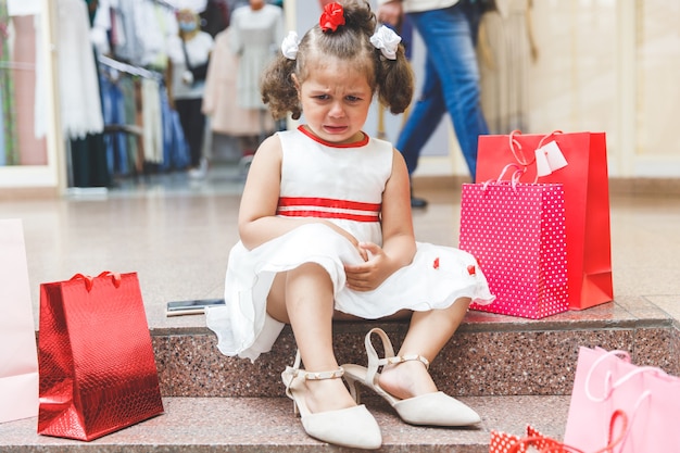 Little girl crying in the mall with colored bags