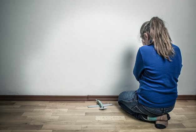 Little girl crying while sitting in an empty room. the child is\
offended. autism
