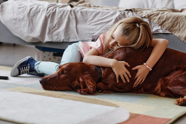 Bambina che coccola con il cane a casa