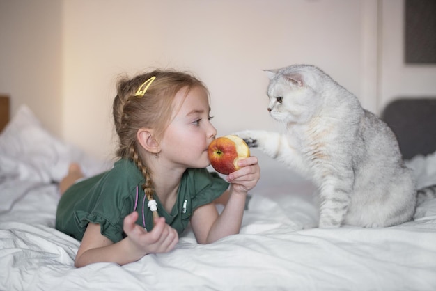 a little girl and a cute cat love to eat an apple