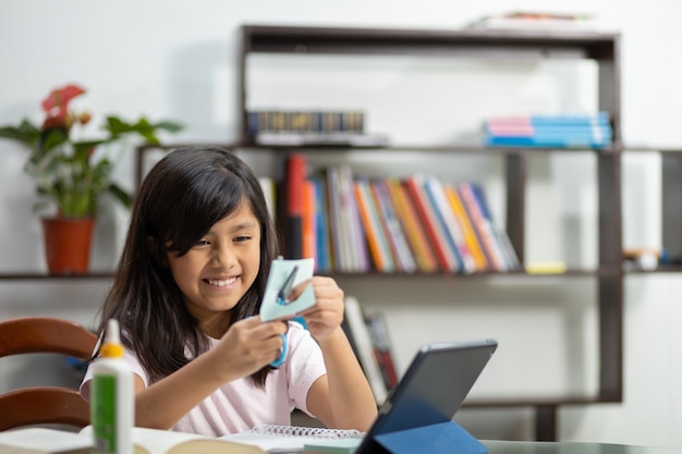 Little girl cutting paper at home