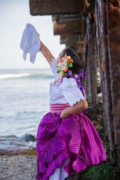 Photo little girl dancing marinera peruvian dance with a handkerchief on the beach