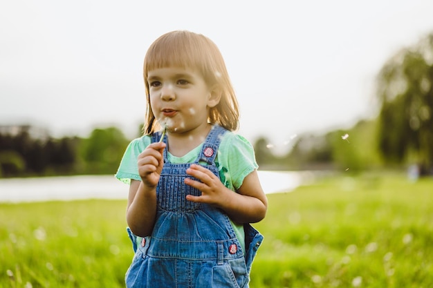 little girl on a dandelion field, at sunset, emotional happy child.