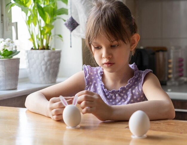 Little girl decorate easter eggs at home preparing for easter concept selective focus