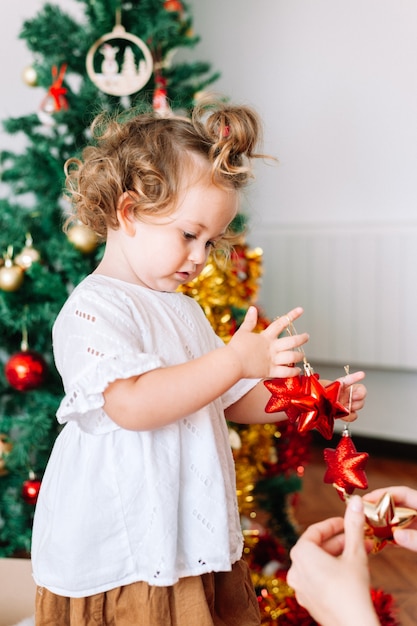 Little girl decoratin Christmas tree with parent