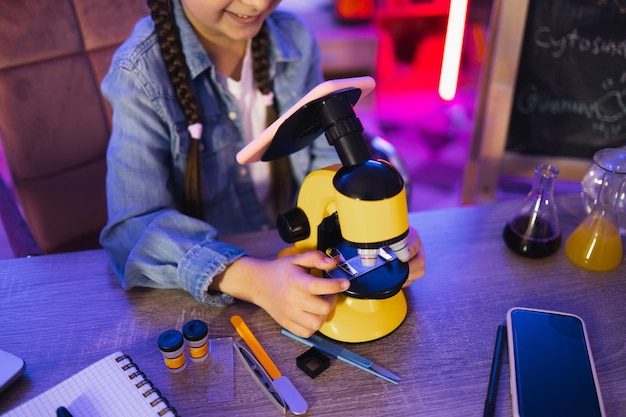 Little girl in denim shirt learning science in evening at home