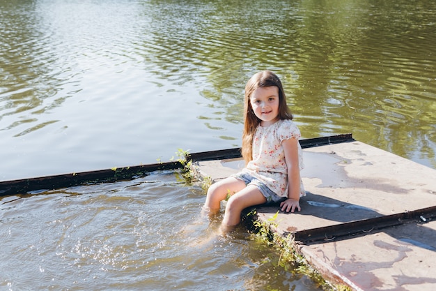 Little girl dipping feet in the water and laughing