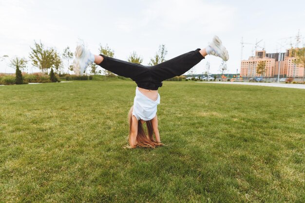 A little girl does gymnastics on the grass a child does gymnastics in the fresh air in the park