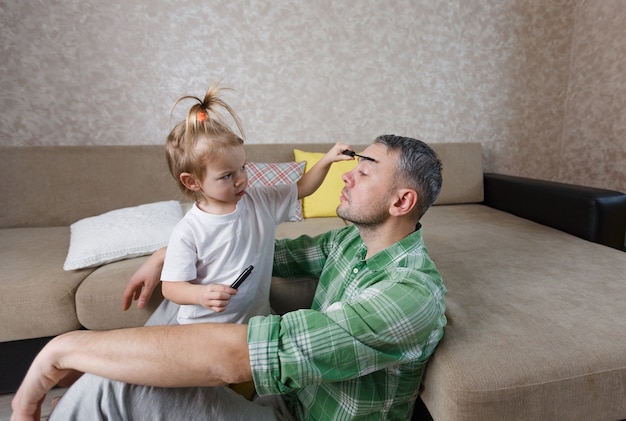 A little girl does makeup to her father during games together