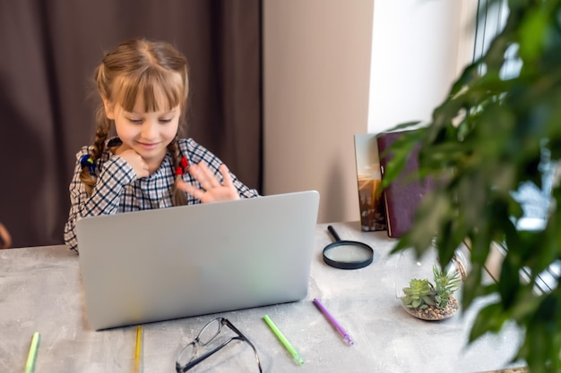 Little girl doing her homework at home and using a laptop