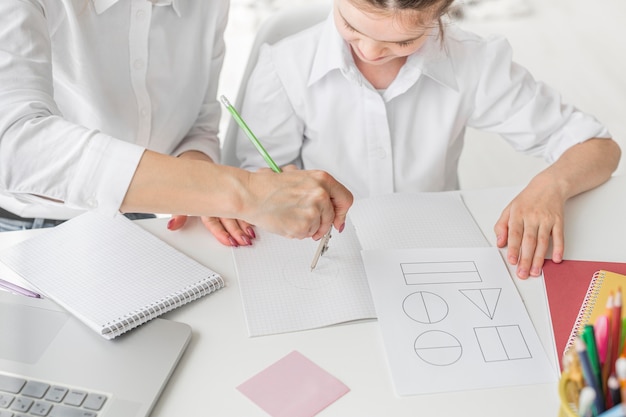 写真 彼女の母親と一緒に宿題をしている女の子