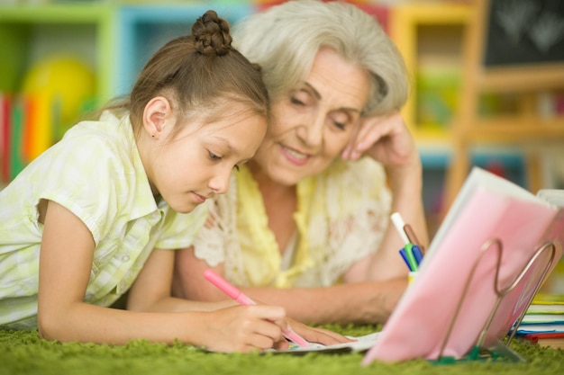 Маленькая девочка делает домашнюю работу с бабушкой дома