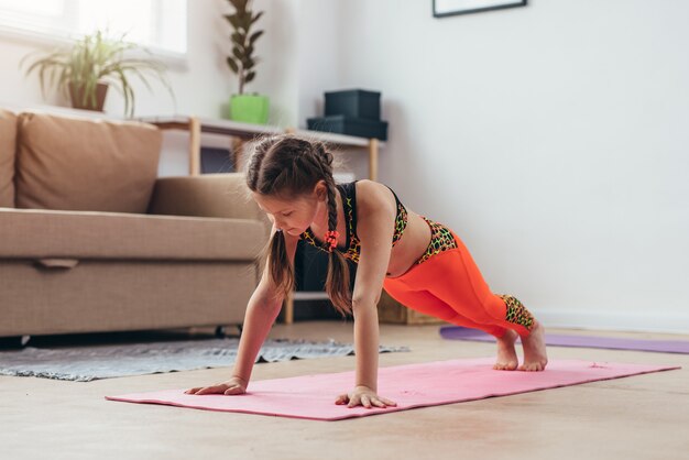 Little girl doing plank exercise at home.