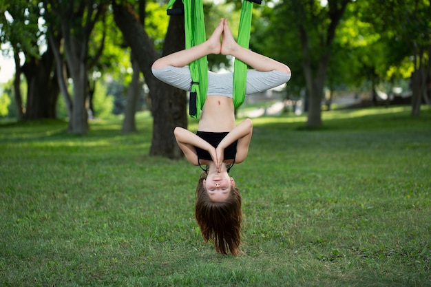 Photo little girl doing yoga exercises with a hammock in the park