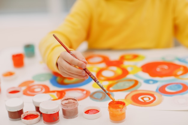 Little girl drawing art picture painting with brush and gouache paints close up